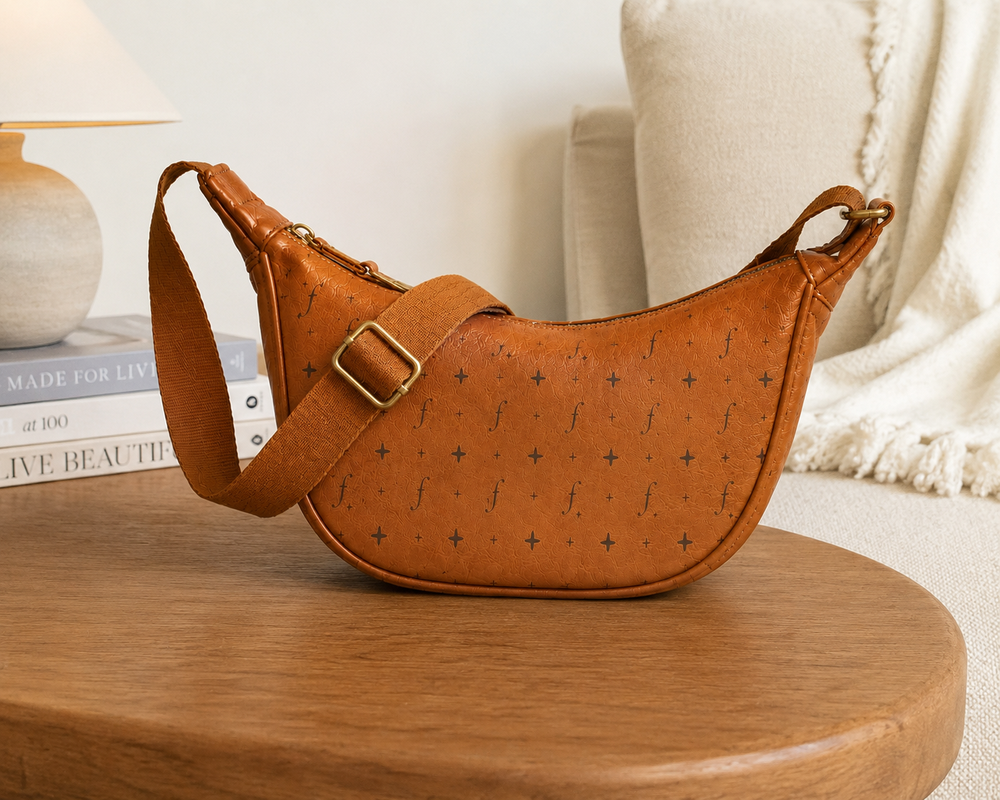 Tan leather crescent shoulder bag on wooden table