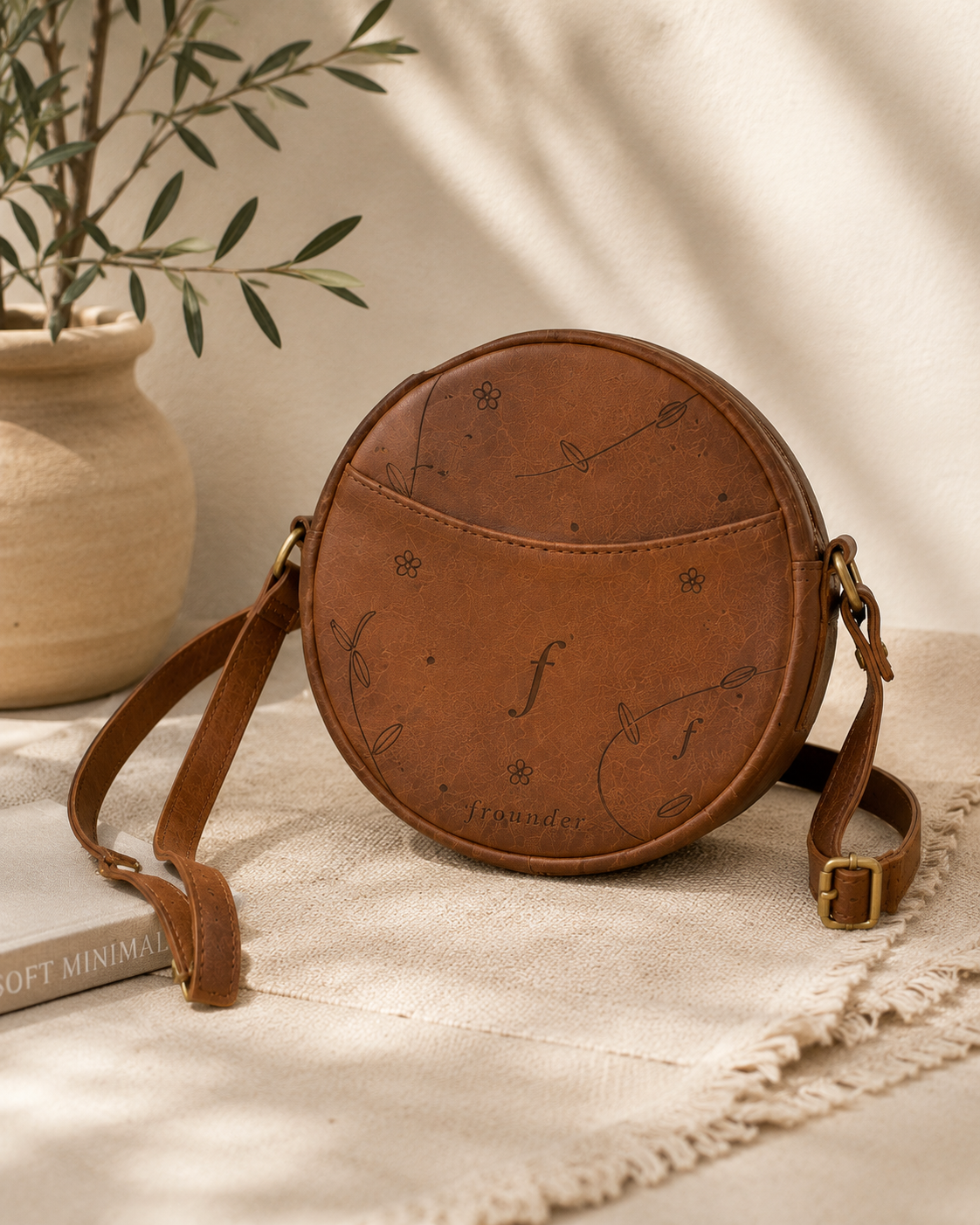 Round brown leather crossbody bag styled on fabric
