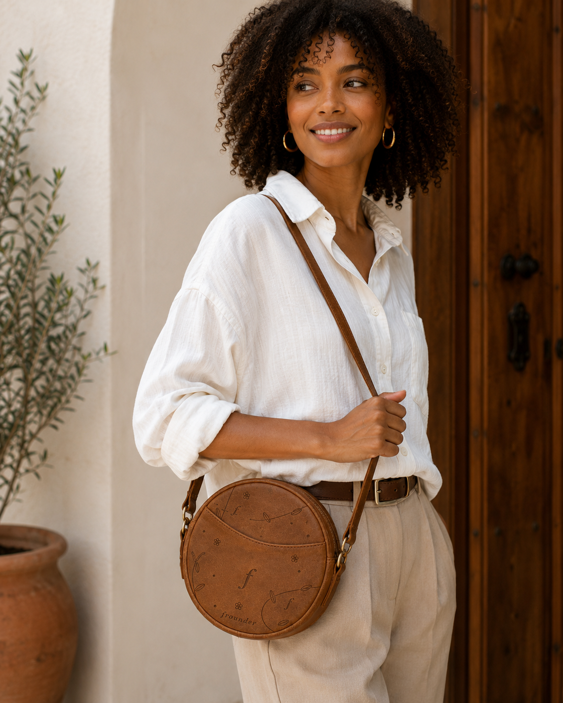 Woman carrying round brown leather crossbody bag