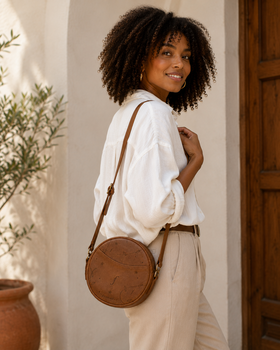 Woman carrying round leather crossbody bag outdoors